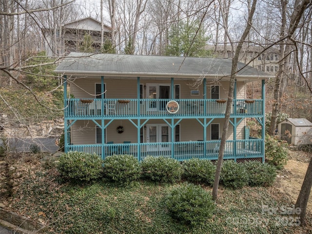 view of front of home with covered porch, a storage unit, an outbuilding, and a balcony