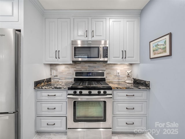 kitchen featuring white cabinetry, stainless steel appliances, decorative backsplash, and dark stone counters