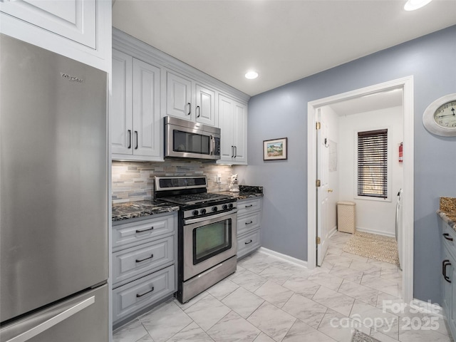 kitchen with stainless steel appliances, white cabinets, marble finish floor, decorative backsplash, and dark stone counters