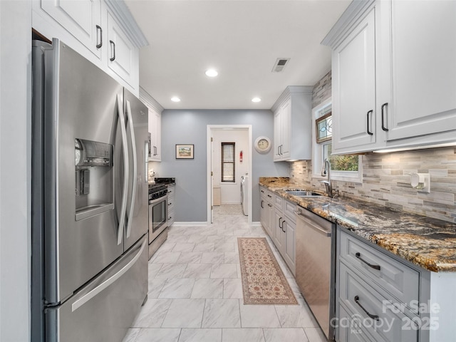 kitchen featuring washer / dryer, visible vents, backsplash, stainless steel appliances, and a sink