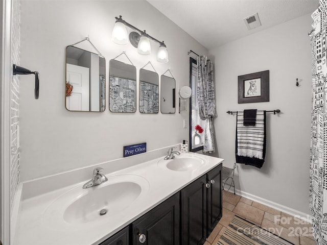 full bath featuring double vanity, a sink, visible vents, and baseboards