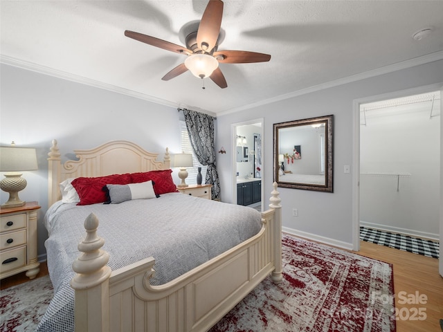 bedroom with baseboards, ceiling fan, ornamental molding, wood finished floors, and ensuite bathroom