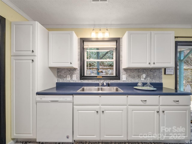 kitchen with dark countertops, decorative backsplash, white cabinets, a sink, and dishwasher