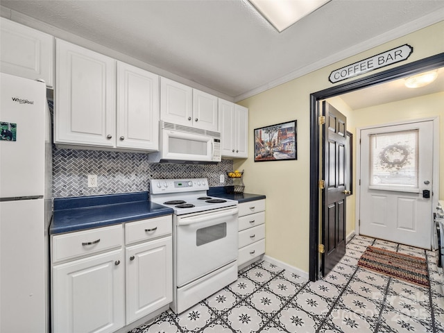 kitchen with dark countertops, white appliances, white cabinets, and decorative backsplash