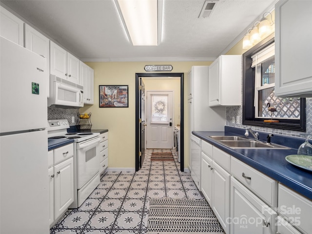 kitchen with dark countertops, visible vents, white cabinetry, a sink, and white appliances