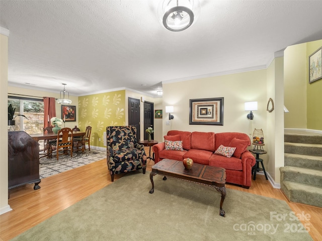 living room featuring a textured ceiling, ornamental molding, stairway, and wood finished floors