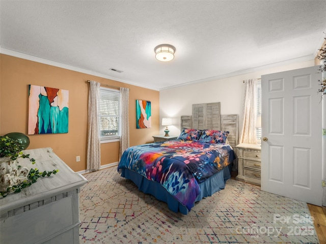 bedroom featuring baseboards, visible vents, ornamental molding, and a textured ceiling