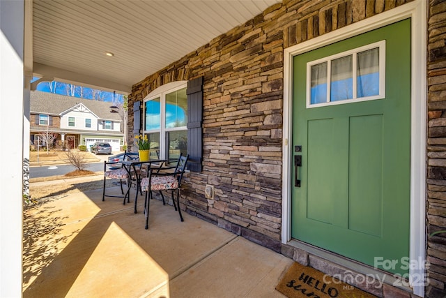 property entrance with stone siding, a porch, and outdoor dining space