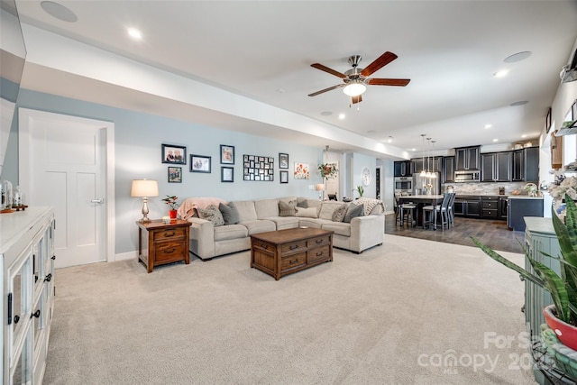 living room featuring light carpet, baseboards, a ceiling fan, and recessed lighting