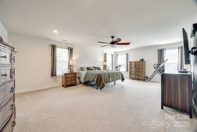 bedroom with a ceiling fan, light colored carpet, and multiple windows