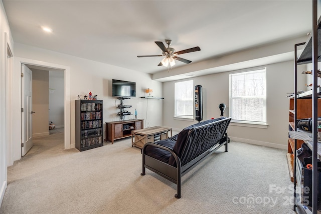 living area with light colored carpet, ceiling fan, and baseboards