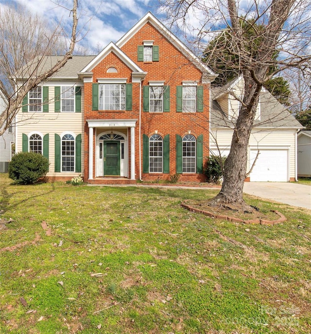 colonial inspired home with a garage, driveway, brick siding, and a front lawn