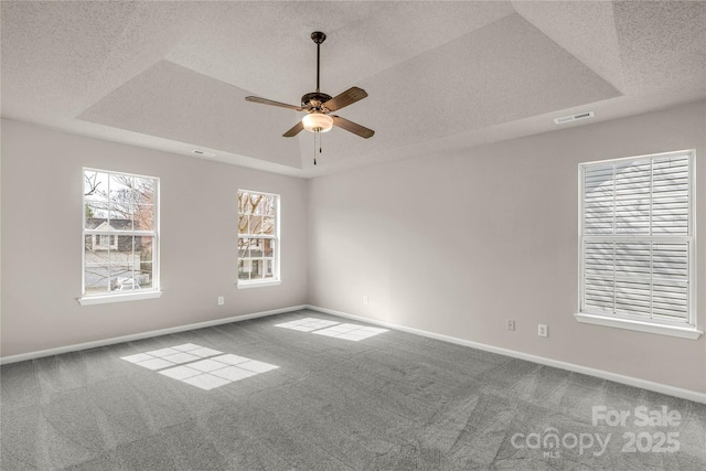 carpeted spare room featuring a raised ceiling, visible vents, a textured ceiling, and baseboards