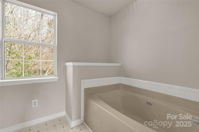 full bathroom with a bath and baseboards