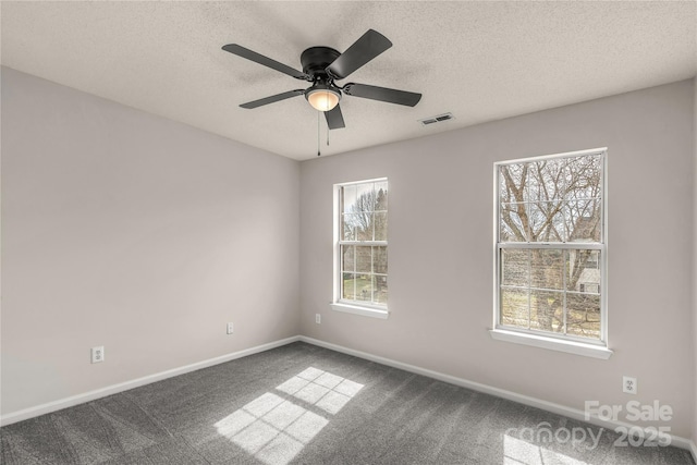 empty room featuring a textured ceiling, ceiling fan, carpet floors, visible vents, and baseboards