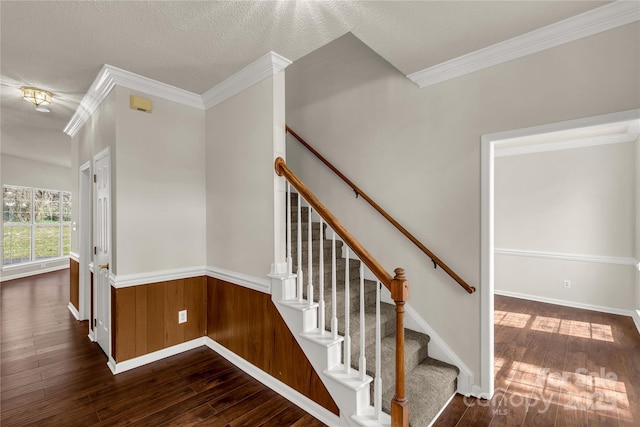 stairs featuring hardwood / wood-style flooring, a textured ceiling, crown molding, and wainscoting