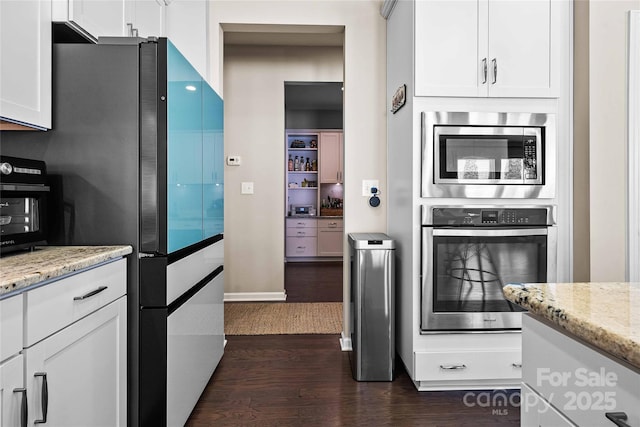 kitchen featuring light stone counters, stainless steel appliances, dark wood finished floors, and white cabinets