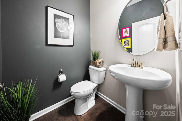 half bath featuring baseboards, toilet, and wood finished floors