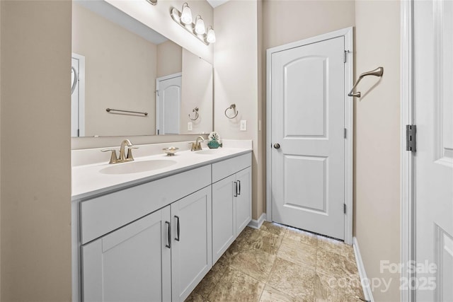 bathroom with double vanity, baseboards, and a sink