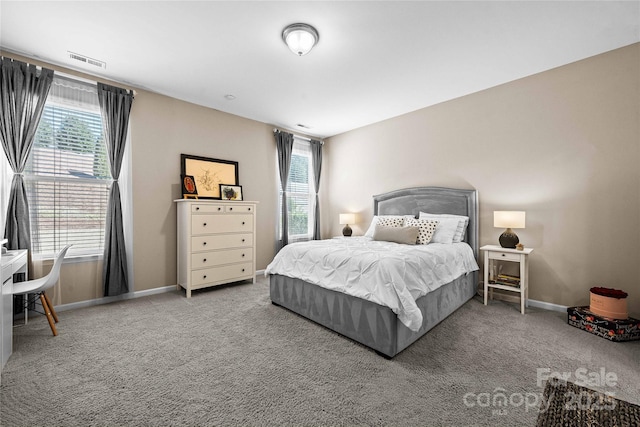 carpeted bedroom featuring multiple windows, baseboards, and visible vents