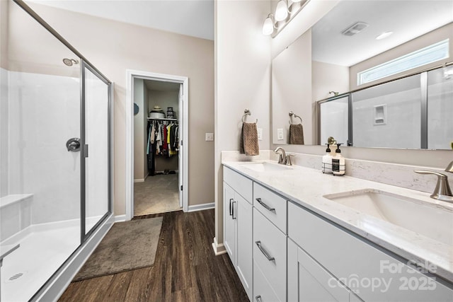 full bathroom with a shower stall, wood finished floors, visible vents, and a sink