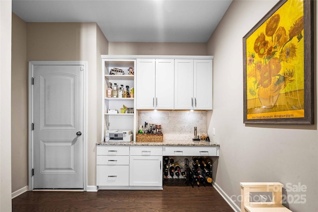 bar featuring tasteful backsplash, a dry bar, baseboards, and dark wood-style flooring