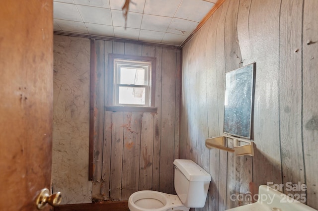 half bathroom with toilet and wooden walls