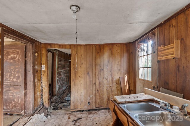 kitchen with brown cabinetry, a sink, and wooden walls