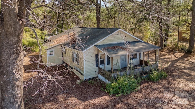 view of front of home featuring covered porch and a wooded view