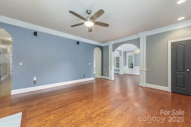 unfurnished room with arched walkways, baseboards, wood finished floors, and crown molding