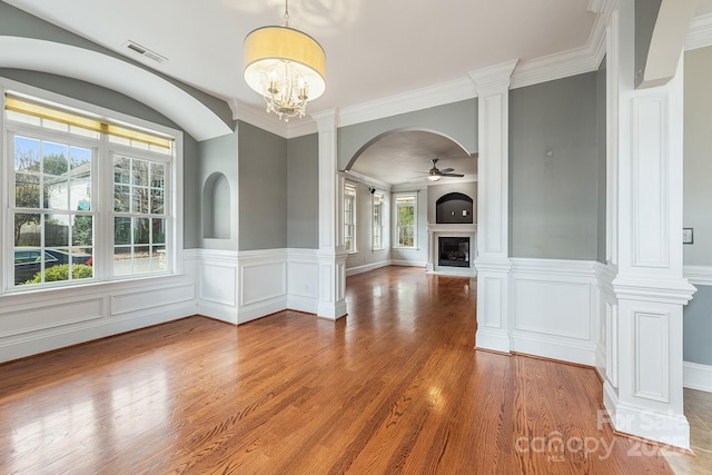 unfurnished living room featuring ceiling fan with notable chandelier, a fireplace, wood finished floors, and visible vents