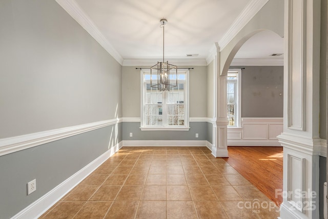 unfurnished dining area with light tile patterned floors, visible vents, arched walkways, crown molding, and a chandelier