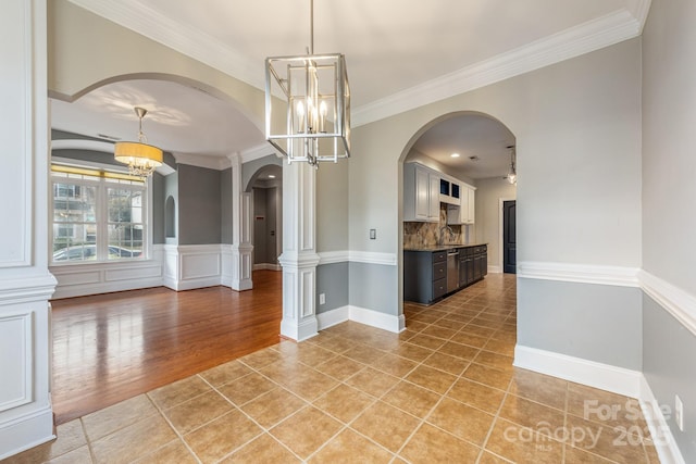 interior space featuring crown molding, a chandelier, a sink, and light tile patterned flooring