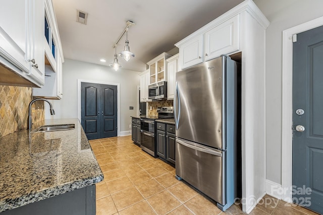 kitchen with light tile patterned floors, decorative backsplash, stainless steel appliances, white cabinetry, and a sink