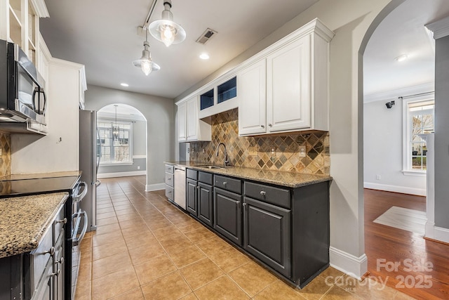 kitchen featuring arched walkways, stainless steel appliances, visible vents, white cabinetry, and a sink