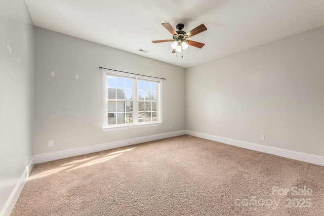 carpeted empty room featuring visible vents, ceiling fan, and baseboards