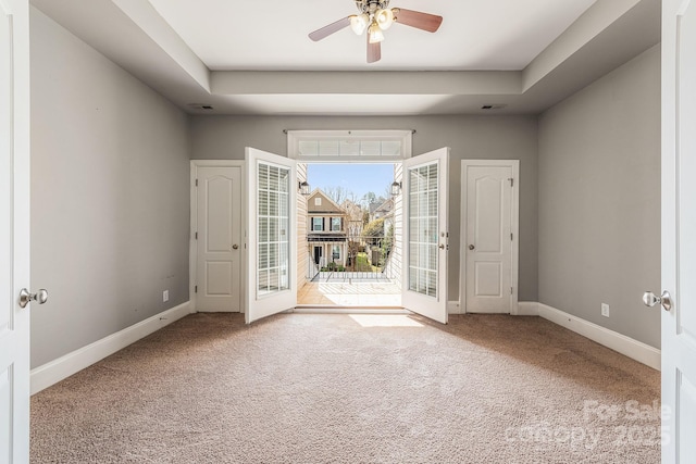 unfurnished room with visible vents, baseboards, a ceiling fan, a tray ceiling, and carpet floors