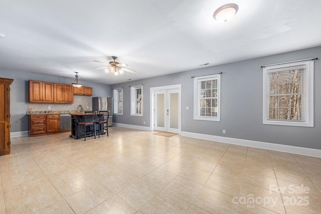 kitchen with tasteful backsplash, baseboards, brown cabinetry, appliances with stainless steel finishes, and a breakfast bar area