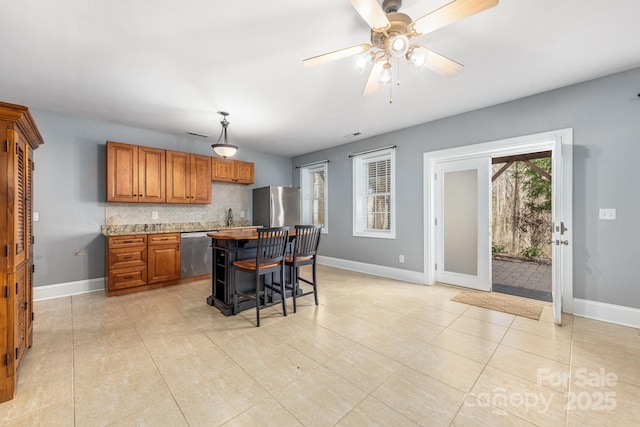 kitchen featuring a center island, brown cabinets, stainless steel appliances, decorative backsplash, and a kitchen bar