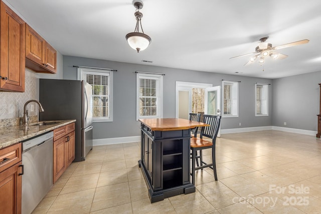 kitchen featuring stainless steel appliances, tasteful backsplash, brown cabinetry, and a healthy amount of sunlight