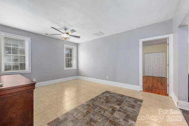 spare room with baseboards, visible vents, and a ceiling fan