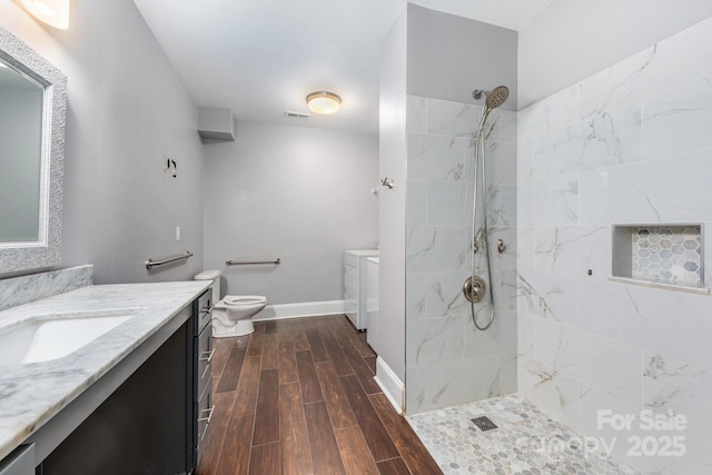 bathroom featuring a marble finish shower, baseboards, independent washer and dryer, vanity, and wood finish floors