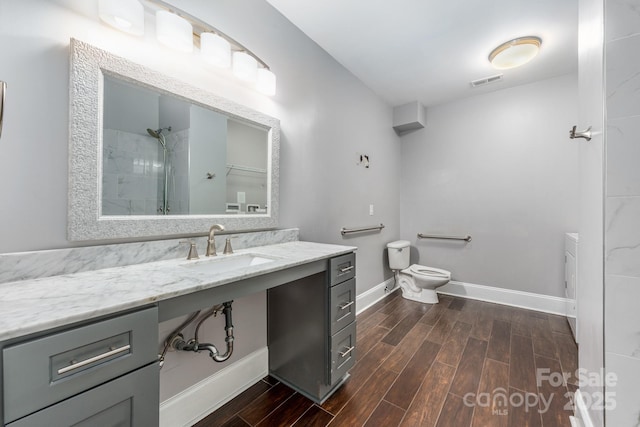 bathroom featuring visible vents, toilet, wood tiled floor, baseboards, and walk in shower