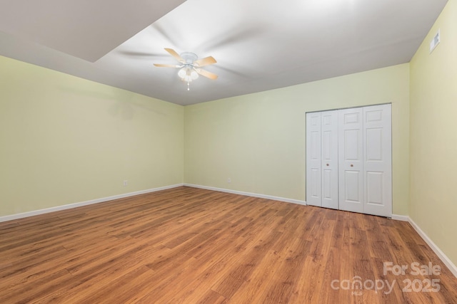 unfurnished bedroom with ceiling fan, a closet, baseboards, and wood finished floors