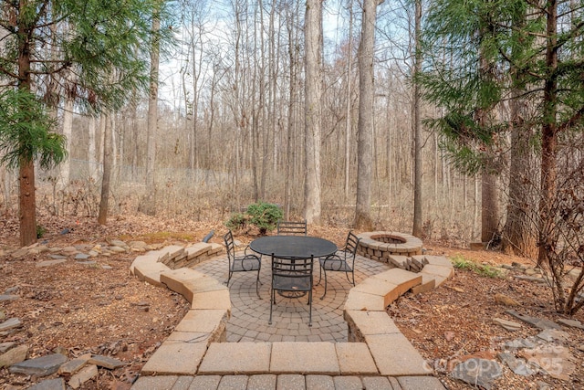 view of patio / terrace featuring a fire pit and a forest view