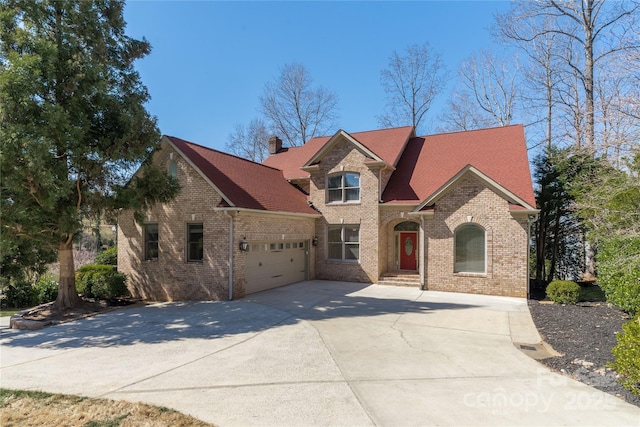 view of front of house featuring a garage, brick siding, driveway, and a chimney