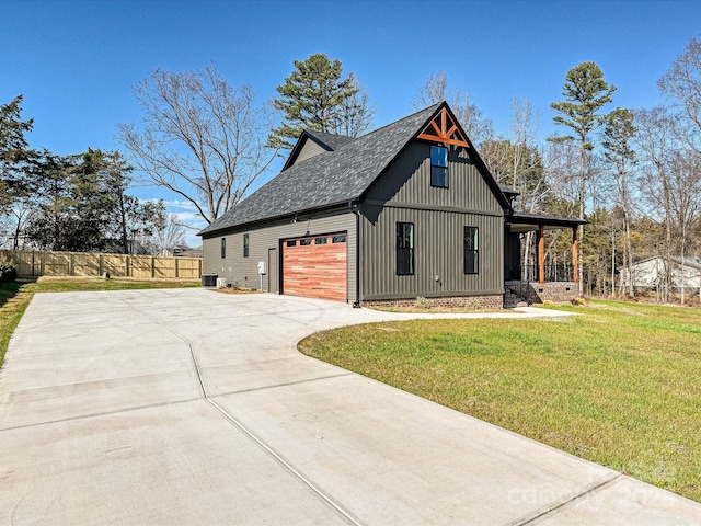 modern inspired farmhouse with a shingled roof, concrete driveway, an attached garage, a front yard, and fence