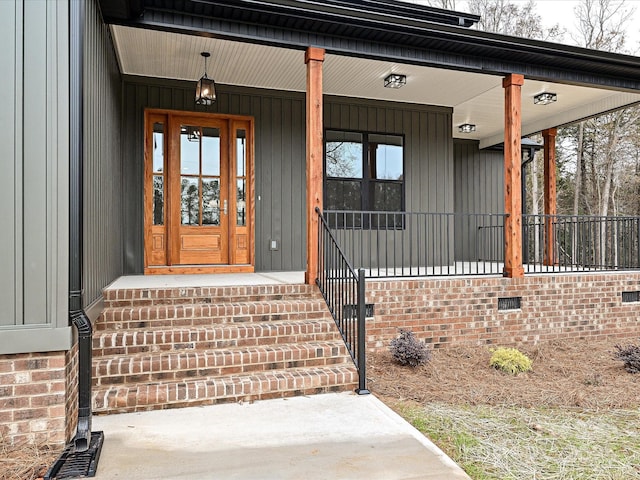 view of exterior entry featuring covered porch, crawl space, and board and batten siding