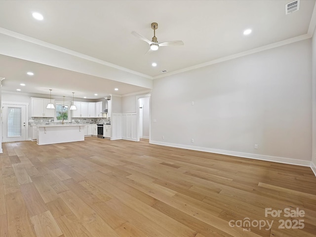 unfurnished living room with visible vents, baseboards, a ceiling fan, ornamental molding, and light wood finished floors