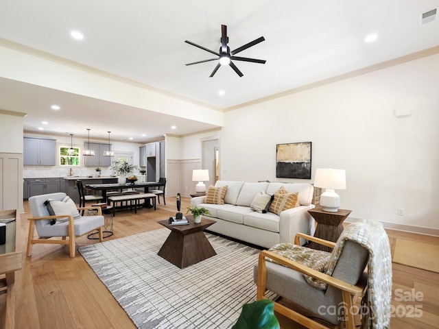 living area featuring light wood-style flooring, ornamental molding, and recessed lighting